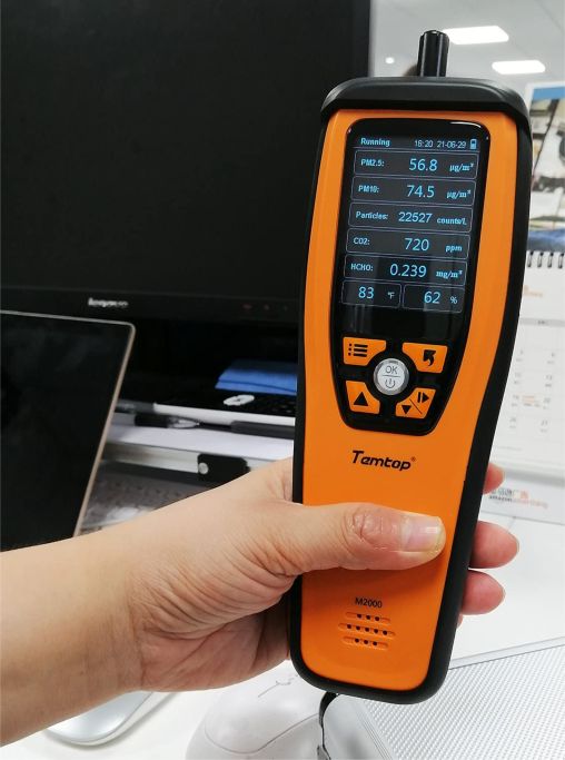 Medidor de qualidade do ar M2000, nas cores laranja e preto. Tem um ecrã LCD e botões de controlo