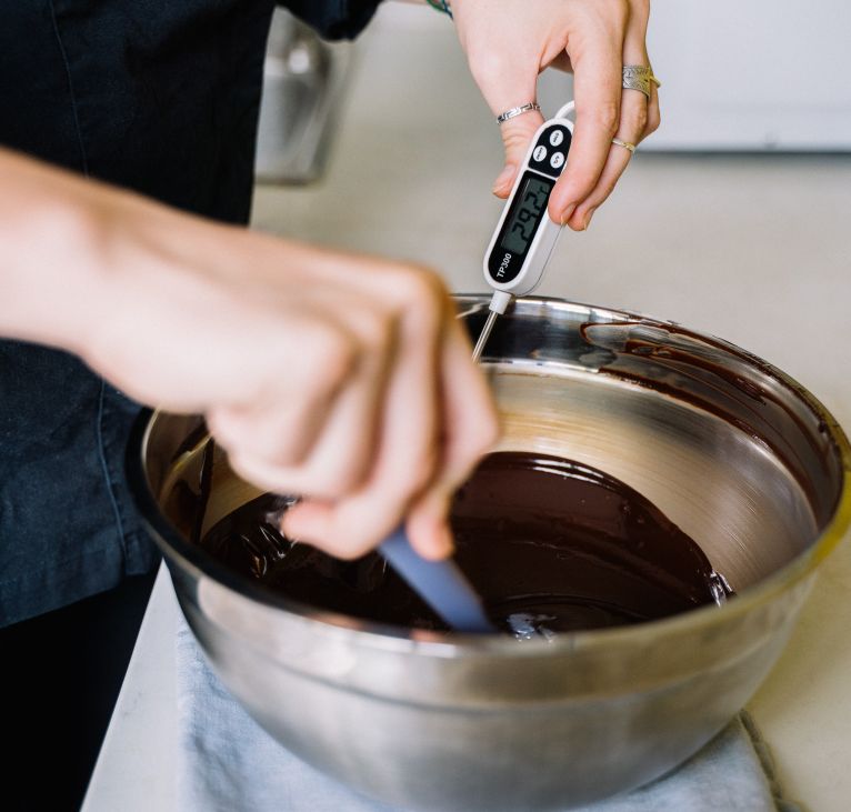 Pasteleira a controlar a temperatura de chocolate com um termómetro de sonda fixa