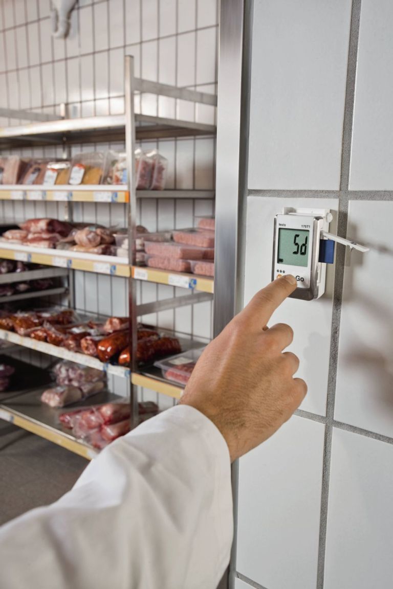 Trabalhador a controlar os valores de uma sala de armazenamento de carnes.